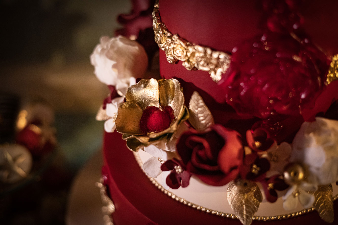 Gold sugar flowers on a deep red ornate wedding cake by GC Couture