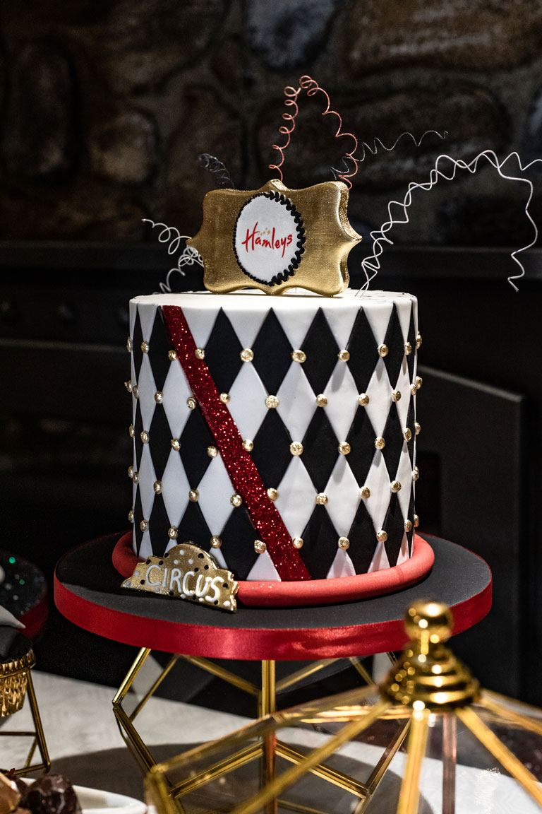 A single tiered black, white, red and gold children's party cake for Hamleys top shop in Regent Street, London