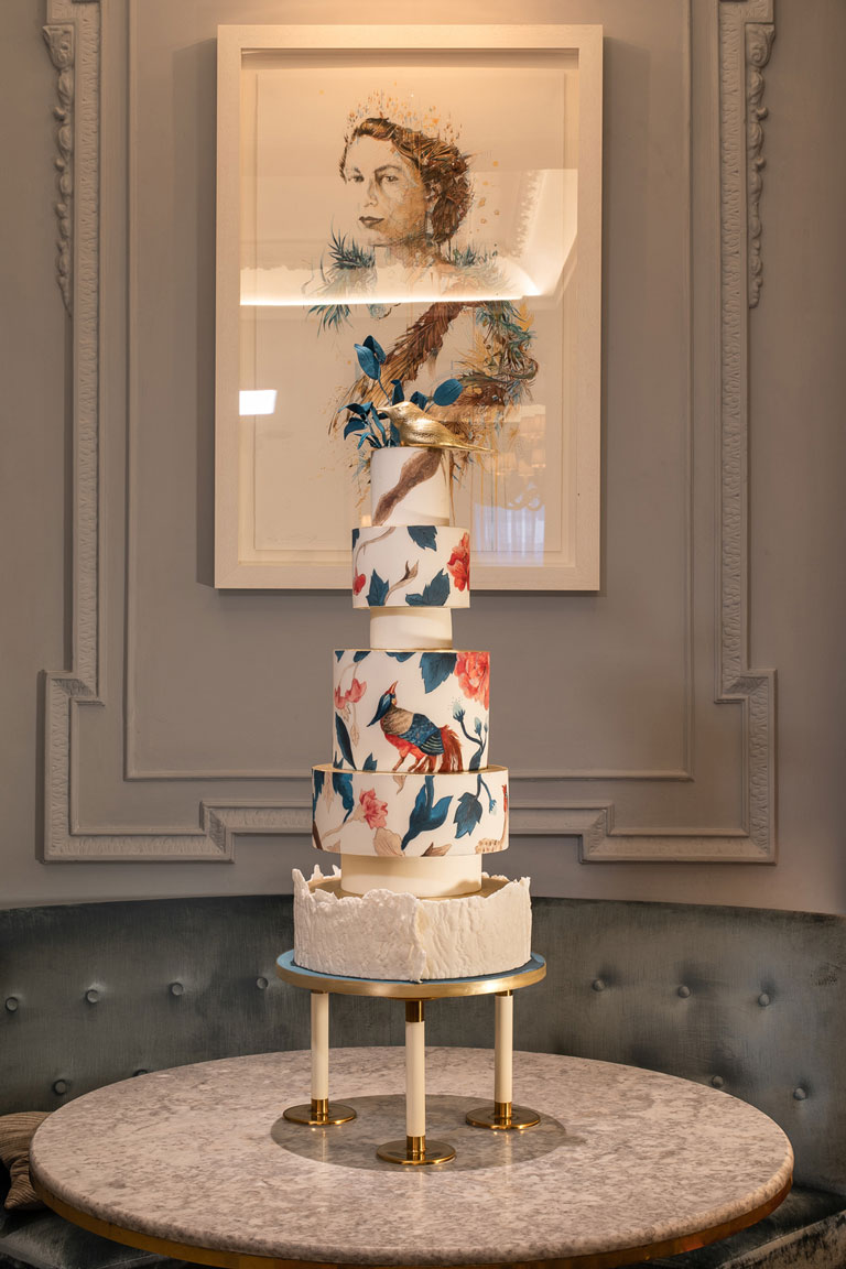Sat on a table in The Game Bird Restaurant is GC Couture's 5-tier cake in front of a painting of Her Majesty the Queen