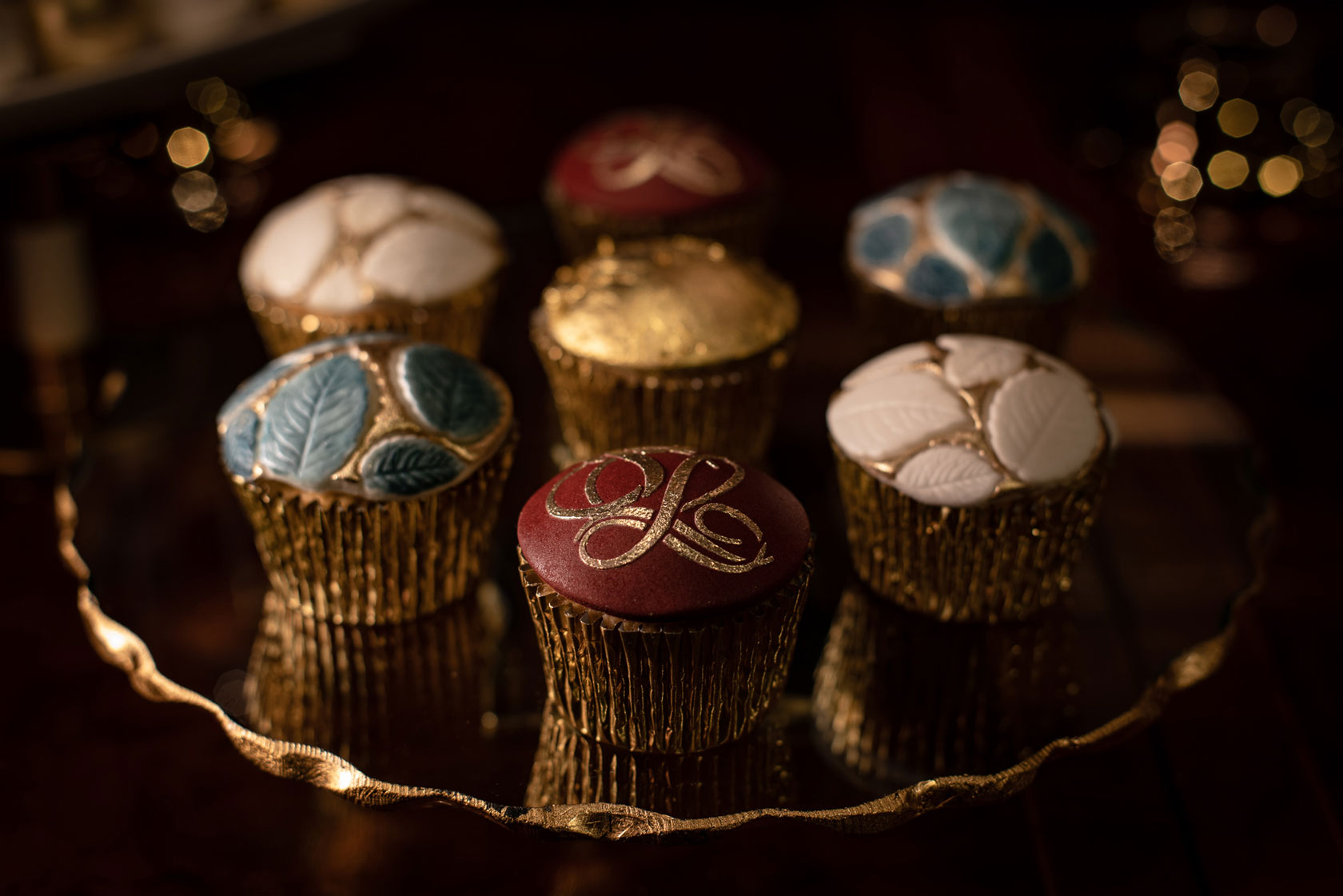 Red, blue, white and gold cupcakes By GC Couture with a delicately handpainted logo on the cupcake at the forefront